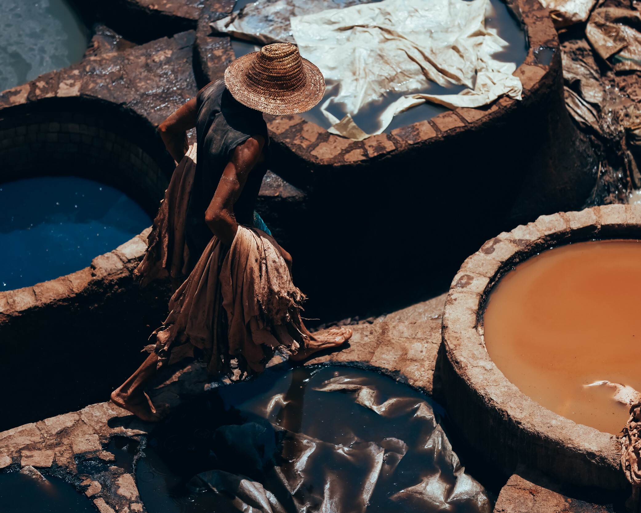 A worker moves between leather dye vats at the traditional tanneries of Fez, Morocco.
